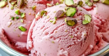 Scoop of watermelon pistachio ice cream in a waffle cone with fresh toppings