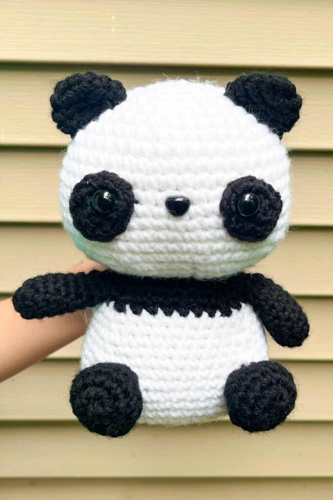 A small, cuddly amigurumi panda plushie in black and white.